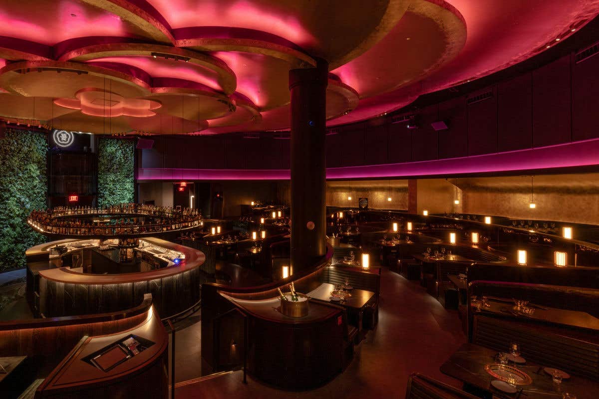 Upscale restaurant interior with curved booths, warm table lighting, and dramatic pink ceiling accents.