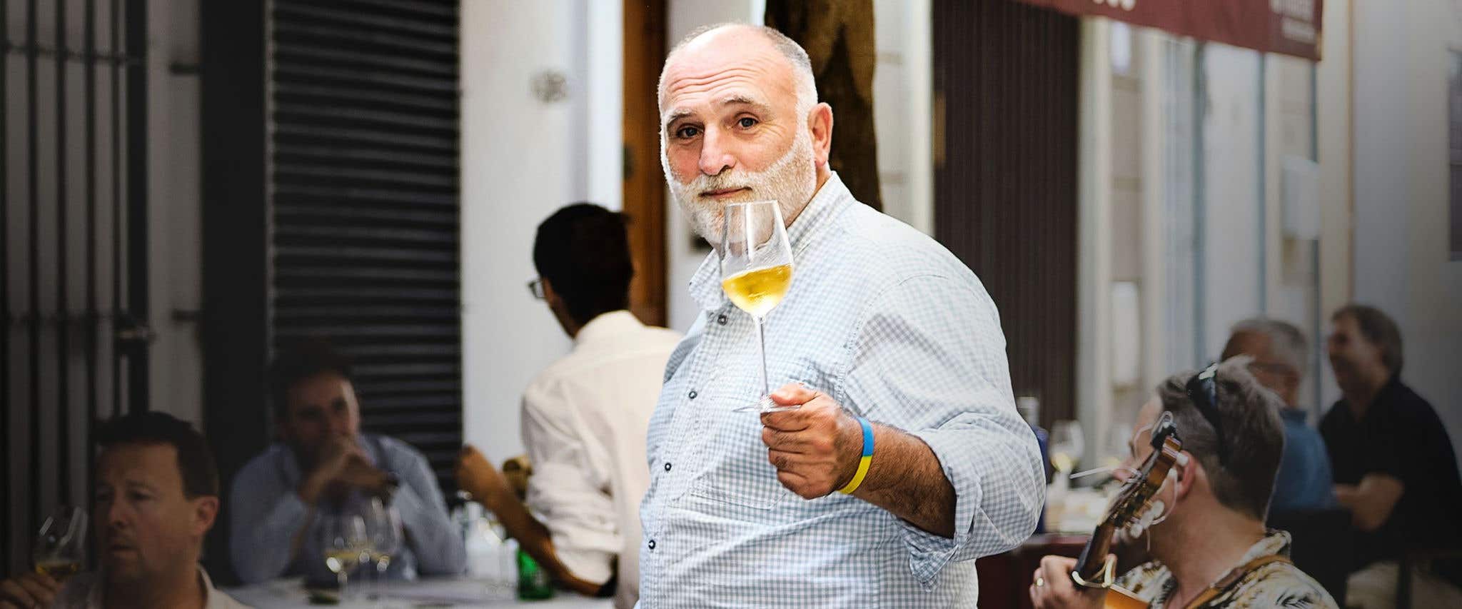 Jose Andres holding a glass of wine looking at the camera.
