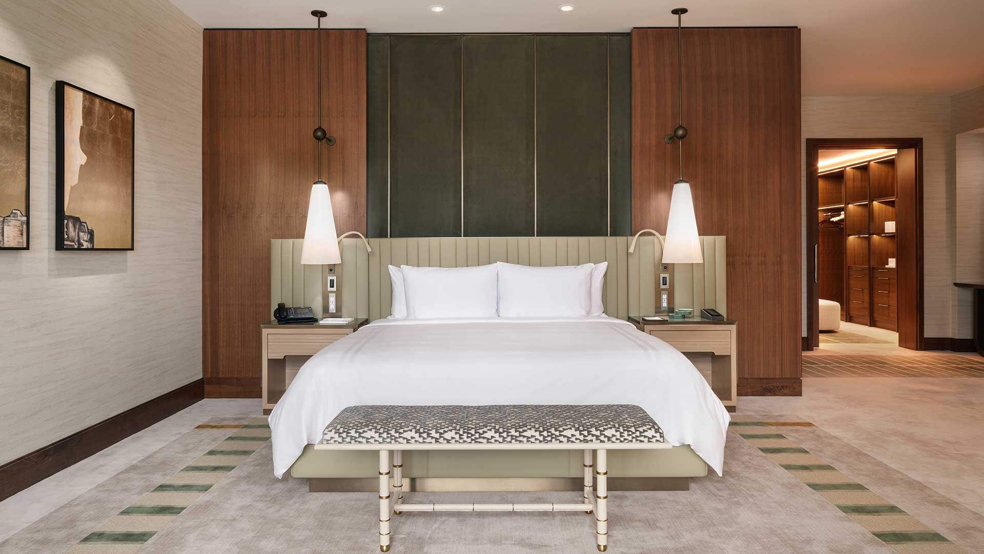 A bedroom designed in muted, natural colors with a king bed and a walk-in closet on the right.