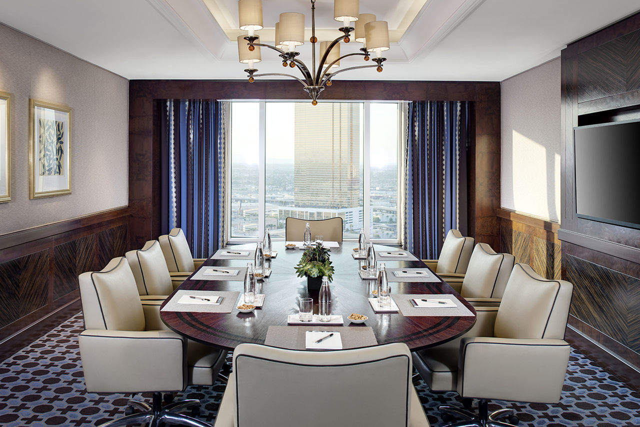 An oval table with 8 chairs in a bright room with a view of Las Vegas